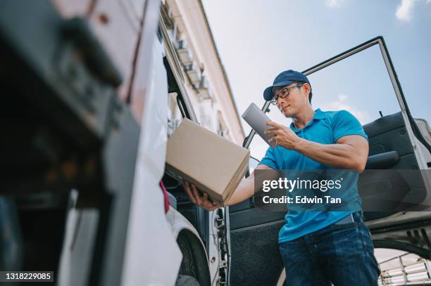 low angle view asian chinese mature male delivery person scanning barcode on package cardboard box using digital tablet - messenger stock pictures, royalty-free photos & images