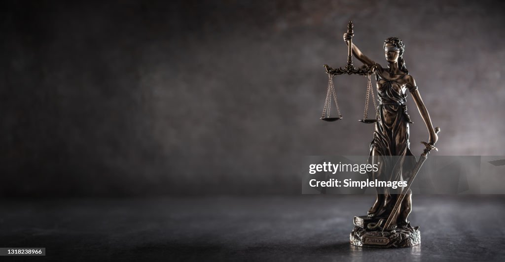 Blind justice symbol on a metallic statue on a dark background.