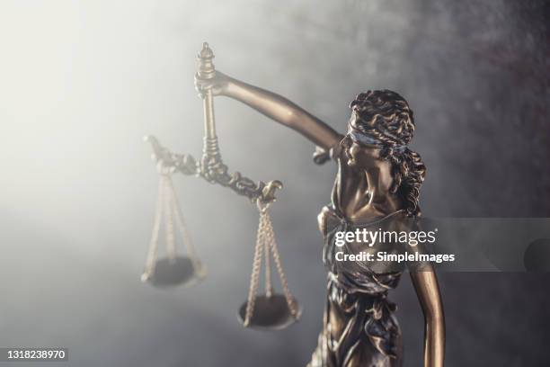 statue symbolizing blindess of justice holds scales against the shining light. - lady justice stock pictures, royalty-free photos & images