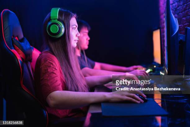 boy and girl playing computer games together under neon lighting - massively multiplayer online game stock pictures, royalty-free photos & images