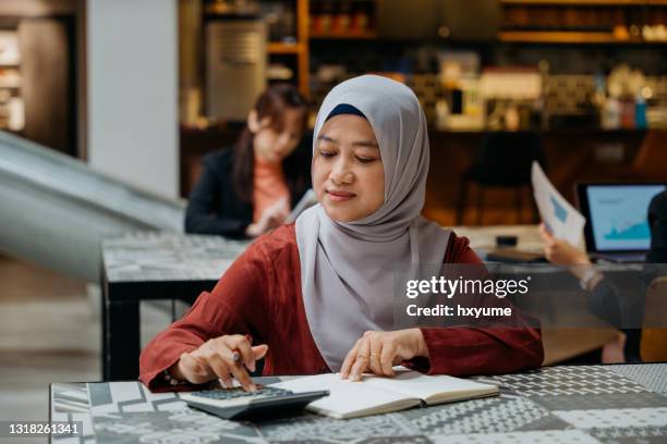 malaiische geschäftsfrau mit taschenrechner für finanzplanung - malay hijab stock-fotos und bilder