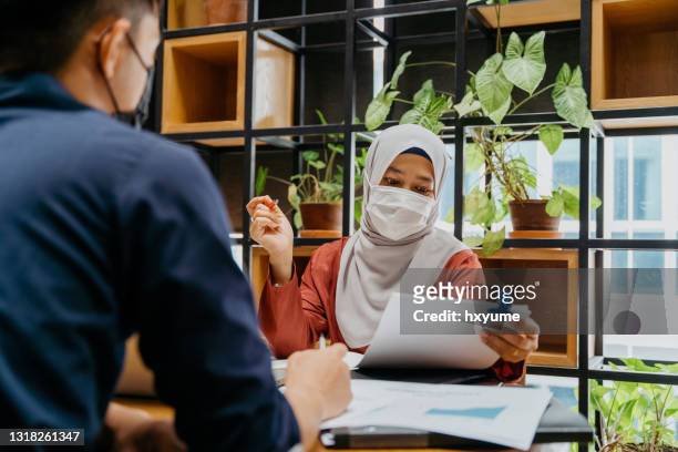muslimische geschäftsfrau mit schützender gesichtsmaske treffen im amt - performance appraisal stock-fotos und bilder
