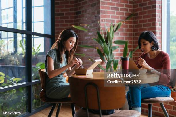 zwei schöne asiatische junge geschäftsfrau mit dem take-out-mittagessen im kuhbüro raum - indian lunch stock-fotos und bilder