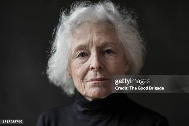 portrait of serious senior woman against black background - femme face photos et images de collection