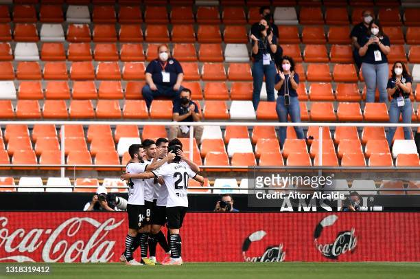 Carlos Soler of Valencia CF celebrates with team mates after scoring their side's third goal as fans wearing face masks applaud during the La Liga...