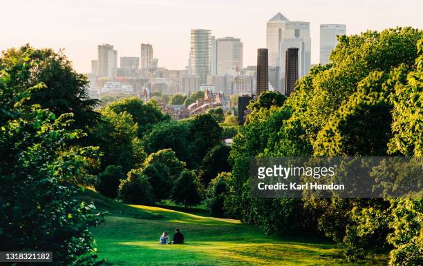 a couple sit in greenwich park, london looking the canary wharf skyline - stock photo - london england stock-fotos und bilder
