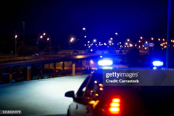 police car with bright sirens and the city in the background - police officer stockfoto's en -beelden