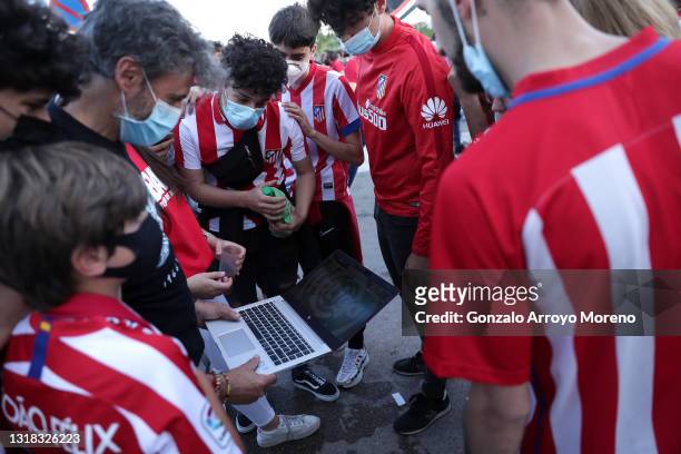 Atletico de Madrid fans gather outside of the stadium and watch the match on a laptop during the La Liga Santander match between Atletico de Madrid...
