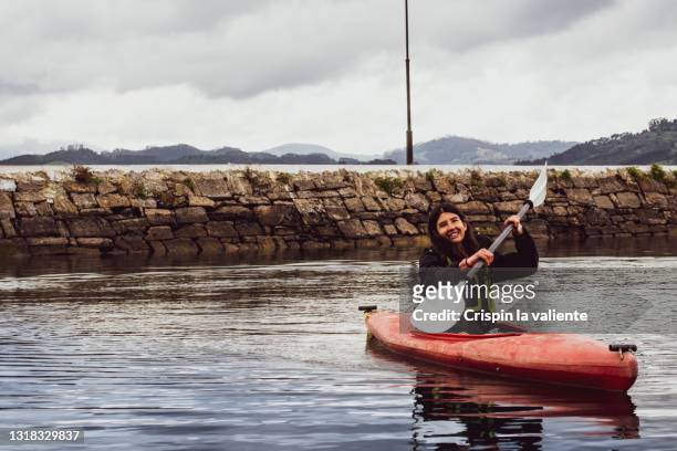 young smiling woman paddling a red canoe in the sea. - sea kayak stock pictures, royalty-free photos & images
