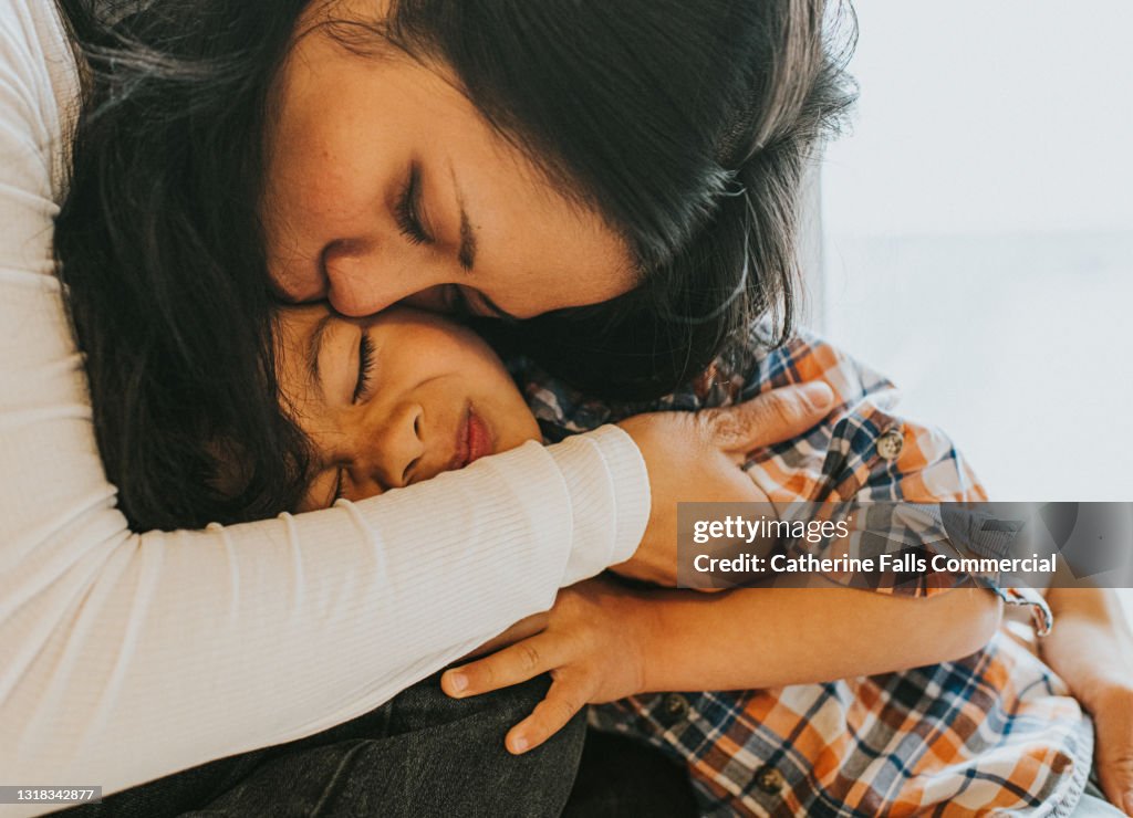 A mother hugs her young son tightly in a loving embrace