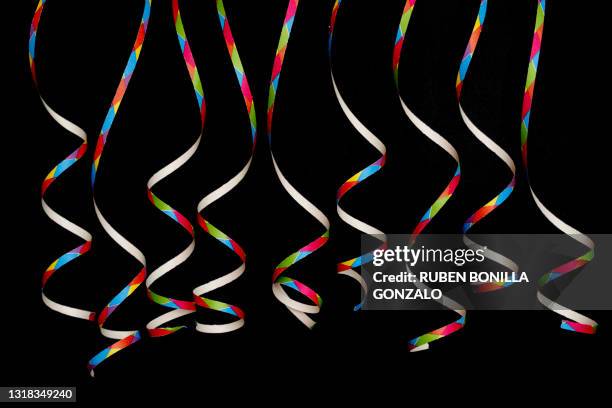 front view of curled up of coloful paper serpentine strips on black background. - up front party stock pictures, royalty-free photos & images