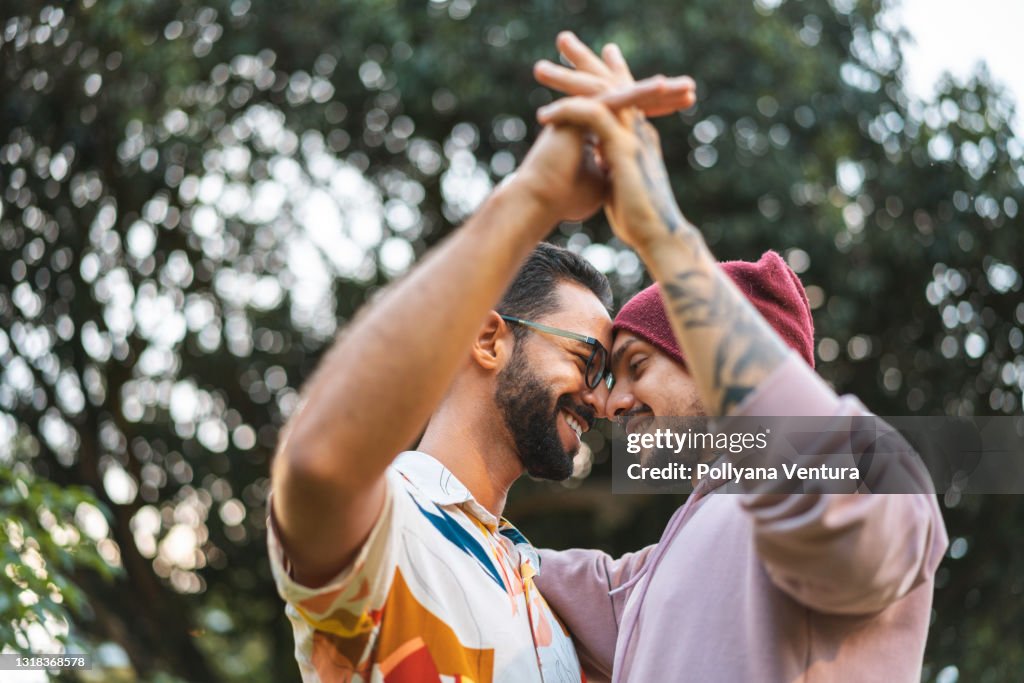 Gay couple touching hands in the public park