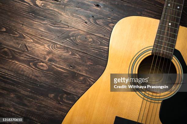 acoustic guitar resting against a wooden background with copy space - chitarra foto e immagini stock