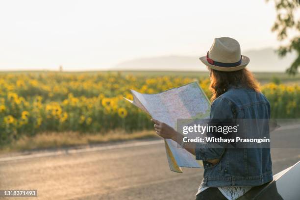 back side of traveler girl searching right direction on map, bright orange sunset light, traveling along europe, freedom and active lifestyle concept - woman map stock pictures, royalty-free photos & images