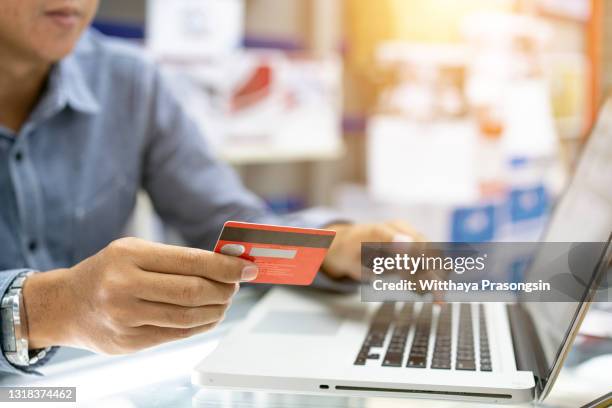 hands holding credit card, typing on the keyboard of laptop, onine shopping detail close up - bank fraud stockfoto's en -beelden