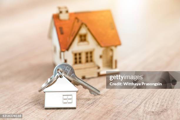 house key on a house shaped keychain resting on wooden floorboards concept for real estate, moving home or renting property - housing infographic stock pictures, royalty-free photos & images
