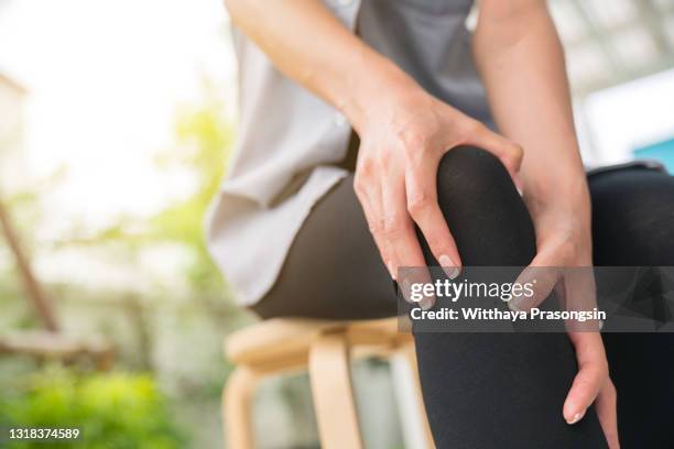 a young woman massaging her painful knee - swollen ankles stock pictures, royalty-free photos & images