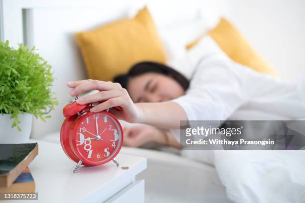 woman turning off the alarm clock - turn fotografías e imágenes de stock