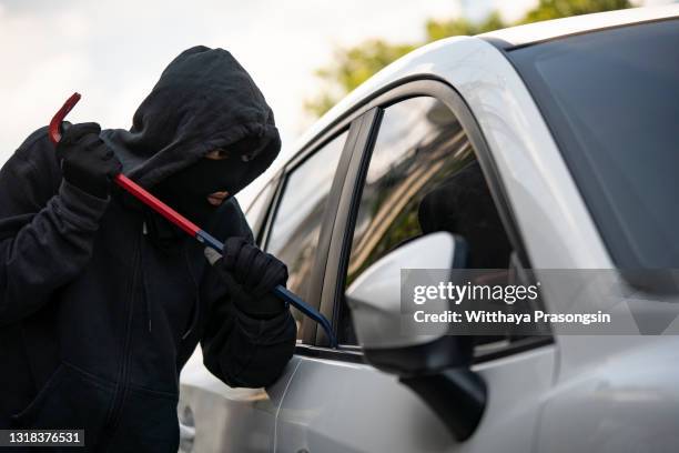 auto thief in black balaclava trying to break into car - voleur photos et images de collection
