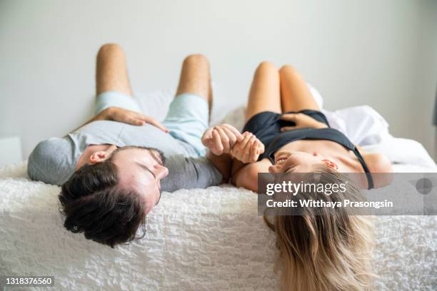 simple joy of loving. attractive young people - junge frau bett sitzen blick in die kamera stock-fotos und bilder