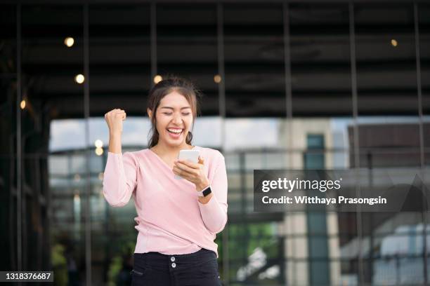 excited student reading good news on line - asian phone stock-fotos und bilder