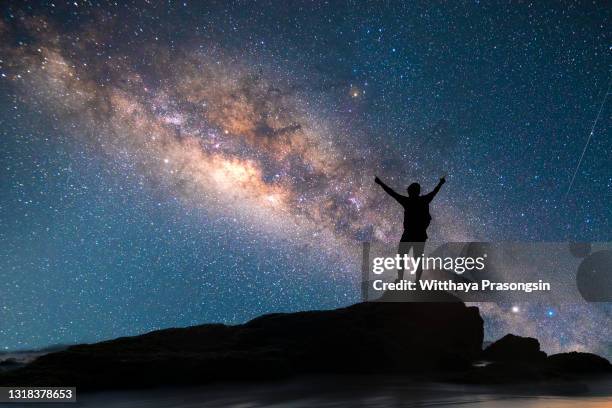 a person is standing next to the milky way galaxy pointing on a bright star. - star sky stock-fotos und bilder