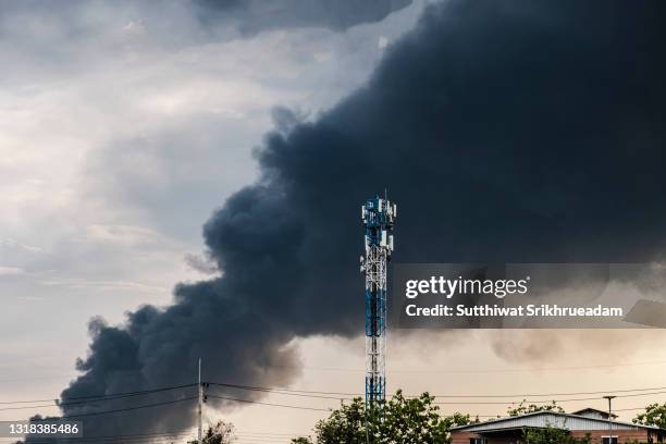 telecommunications base station tower against black smoke filled sky as fire burns plastics warehouse in bangkok,thailand - skog stock pictures, royalty-free photos & images