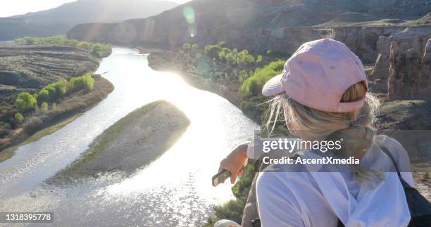 mature hiker pauses on edge of canyon with her mobile phone - fruita colorado stock pictures, royalty-free photos & images