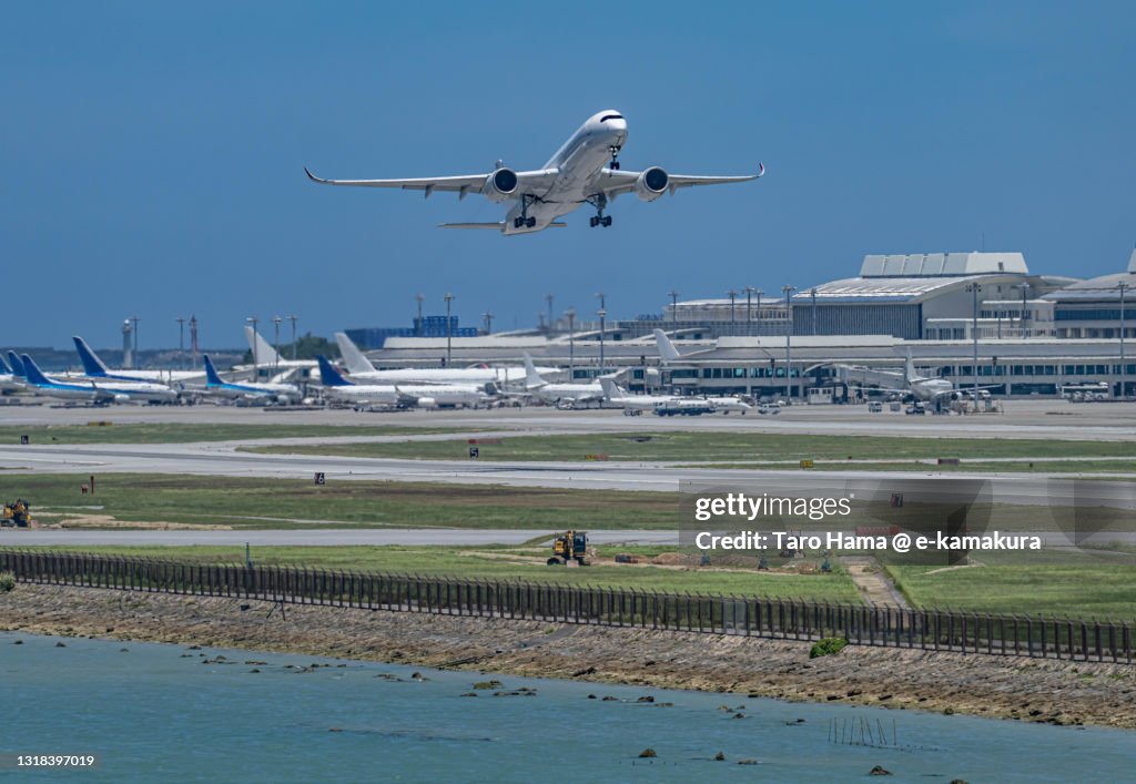 The airplane flying over the beach in Naha city of Japan