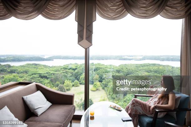 een vrouw op vakantie die door venster het drinken wijn ontspant - single rose stockfoto's en -beelden