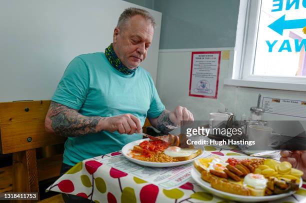 Customer enjoys an early morning Full English Breakfast at an indoor table at Smokey Joe's Cafe, Scorrier, on May 17, 2021 in Falmouth, England....