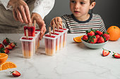 Woman and son making orange and strawberry ice pops