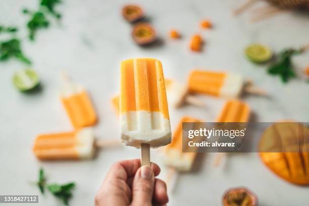 mango-joghurt-eis in der hand - freezing hands stock-fotos und bilder