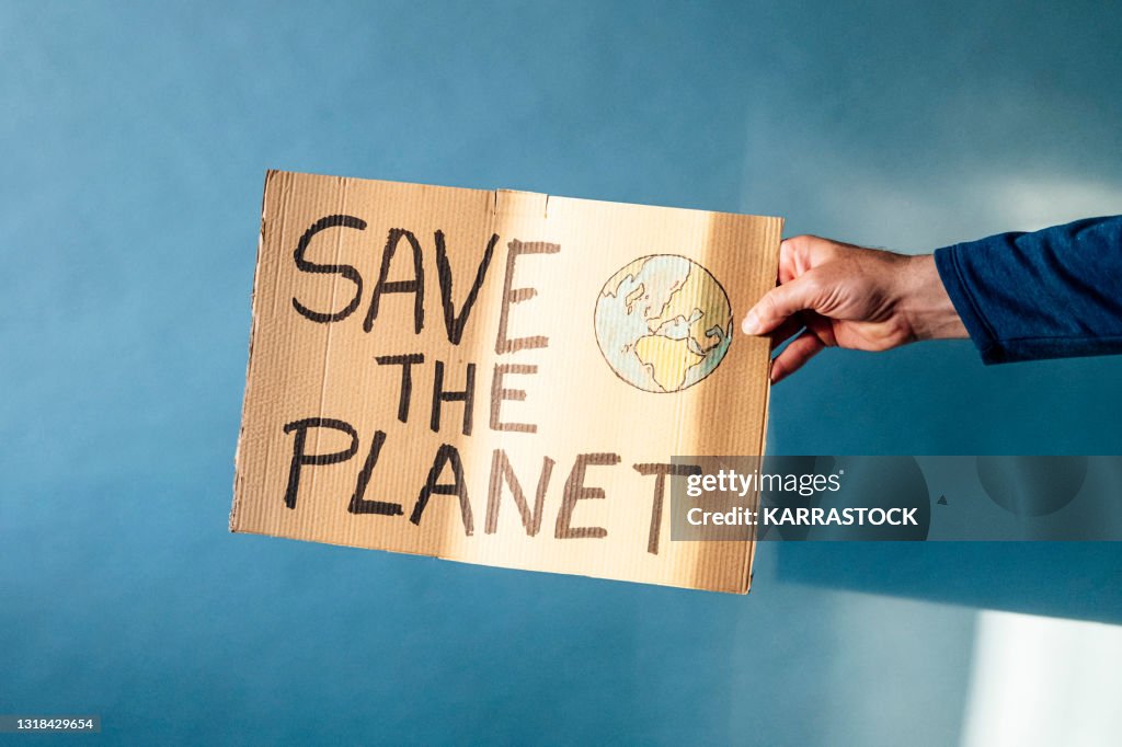 Man's hand holding a cardboard sign that says SAVE THE PLANET