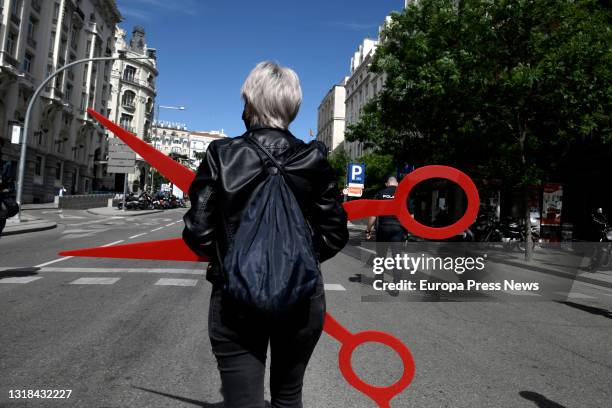 Person of the aesthetics sector stands with some giant scissors at a demonstration organized from the Paseo del Prado to the Congress of Deputies, on...