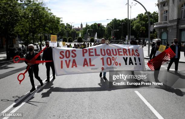 Groups of people demonstrate with a banner where you can read "SOS PELUQUERIAS IVA AL 10% YA!" in a demonstration organized from the Paseo del Prado...