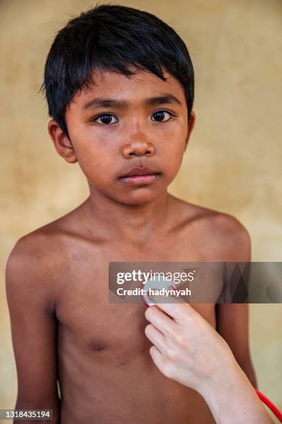 doctor examining young cambodian boy in small village, tonle sap, cambodia - doctors without borders stock pictures, royalty-free photos & images