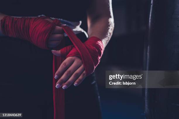 onherkenbare vrouwelijke bokser het toepassen van zelfklevend verband bij de hand voor bokstraining - mixed martial arts stockfoto's en -beelden