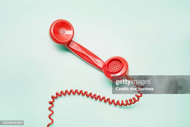 red old-fashioned telephone receiver on turquoise background - telephone receiver stock pictures, royalty-free photos & images