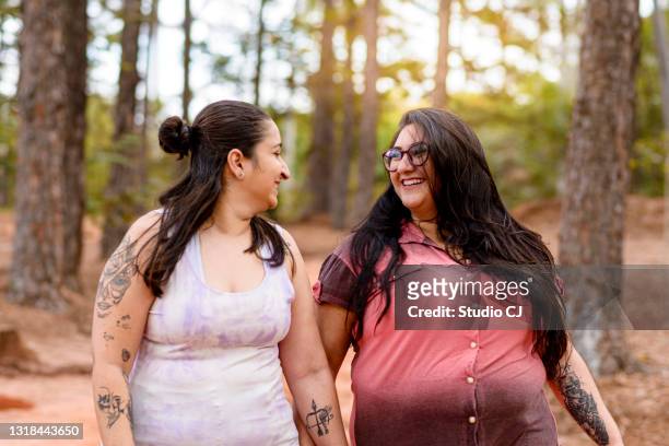 couple of women in love smiling during walk in wooded forest - rural couple young stock pictures, royalty-free photos & images