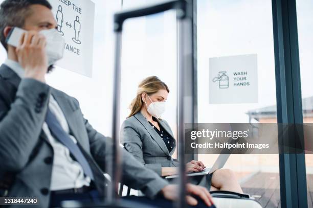 man and woman waiting at the gate lounge at the airport, business and coronavirus concept. - airport mask stock pictures, royalty-free photos & images