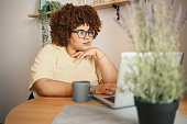 Attractive happy stylish plus size African black woman student afro hair in glasses studying online working on laptop computer at home office workspace. Diversity. Remote work, distance education.