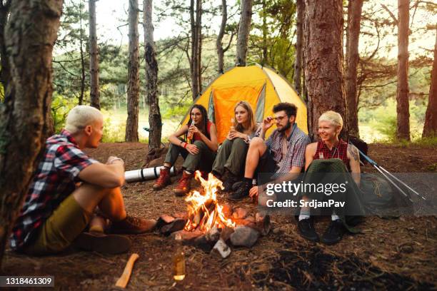 happy young campers sitting next to the bonfire and telling stories - campfire storytelling stock pictures, royalty-free photos & images