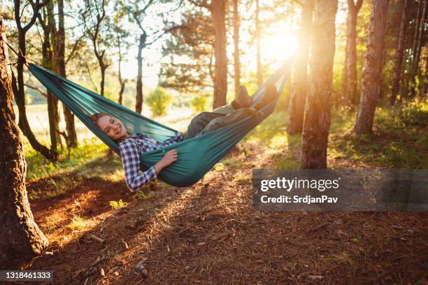 happy young woman resting in a hammock in the woods - hammock camping stock pictures, royalty-free photos & images