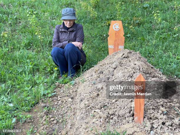 senior woman beside husband's grave - trennungsschmerz stock-fotos und bilder