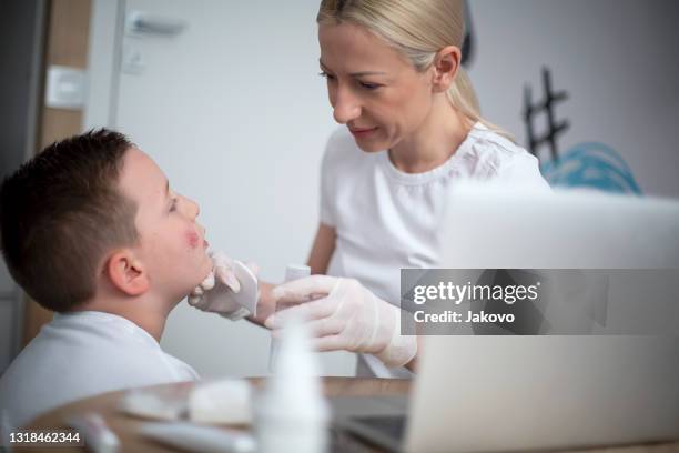 mother cleaning her son's wound on his cheek - doctor looking down stock pictures, royalty-free photos & images