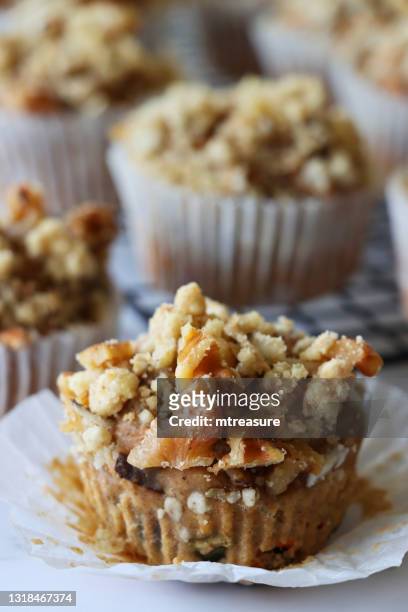 close-up image of homemade apple muffin, unwrapped from paper cake case, topped with crumble, background of wire metal cooling rack full of cakes, marble effect surface, focus on foreground - brown apple stock pictures, royalty-free photos & images
