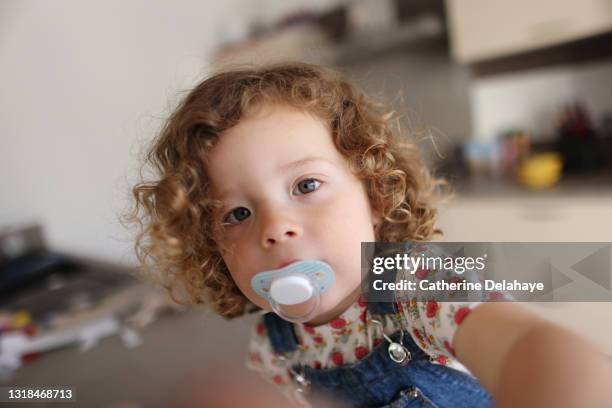 a 2 year old girl with pacifier at home - chupeta imagens e fotografias de stock
