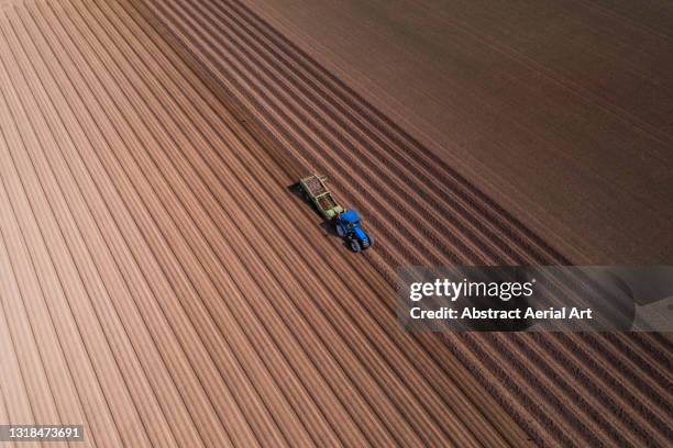 high angle perspective showing a tractor working in a plowed field, england, united kingdom - campo arato foto e immagini stock