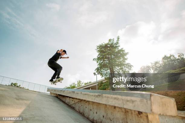 asian male skateboarder catches some air in a skate park - wide shot stock pictures, royalty-free photos & images